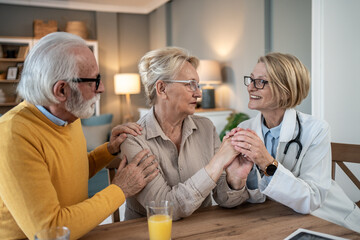 Senior couple receiving comforting support from doctor at home