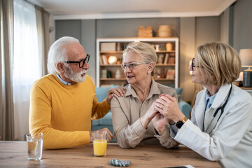 Senior couple receiving comforting support from doctor at home
