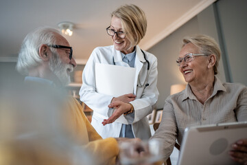Female doctor comforting senior couple at home during home visit