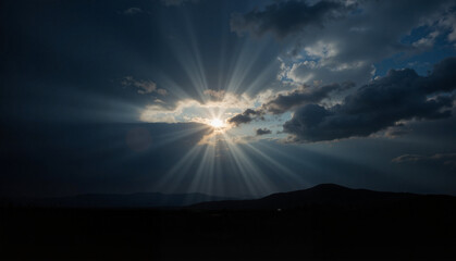 Hopeful light piercing dark clouds, solemn reflection