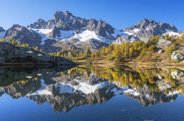 Fototapeta premium Majestic Mountain Landscape with Snow-Capped Peaks and Crystal Clear Lake Surrounded by Autumn Trees and Clear Blue Sky in Stunning Natural Setting
