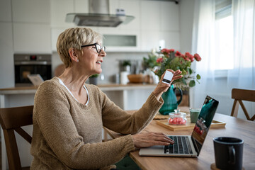 Senior woman making online payment with credit card at home