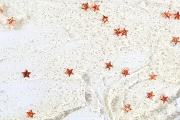 Sparkling red star confetti on glittery white surface for festive celebration decor.
