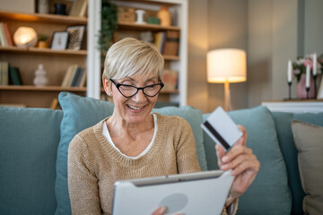 Senior woman using digital tablet and credit card for online shopping at home