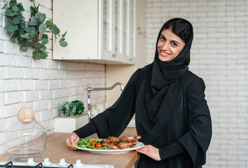 Beautiful arabian woman with abaya preparing lunch for the eid mubarak holidays.