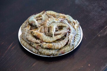 Fresh shrimps on white round plate isolated in selective focus. Shrimp head