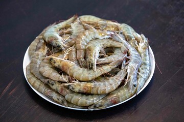 Fresh shrimps on white round plate isolated in selective focus. Shrimp head