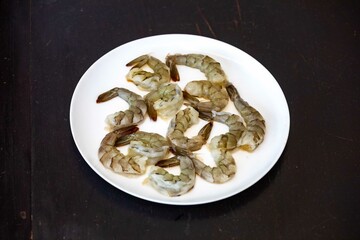Fresh shrimps on white round plate isolated in selective focus. Shrimp head
