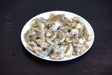 Fresh shrimps on white round plate isolated in selective focus. Shrimp head