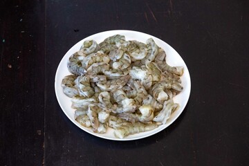 Fresh shrimps on white round plate isolated in selective focus. Shrimp head