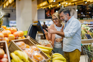 Senior couple weighing fruit at supermarket self service scale
