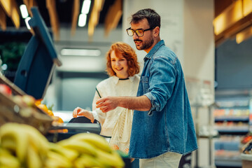 Couple weighing fresh produce at supermarket checkout, embracing healthy lifestyle