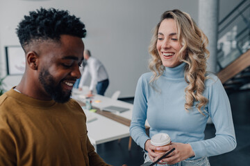 Smiling business colleagues chatting during coffee break in modern office