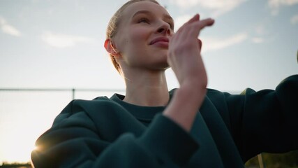 Close-up of lady in green sweater playing volleyball outdoors with sunlight creating glow around. Intense action shot capturing movement and energy of player during game with warm natural