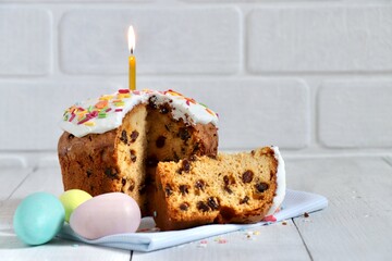 Delicious cake with burning candle and painted eggs on light background. Traditional food for Easter holiday. Holiday concept, festive composition. Copy space.