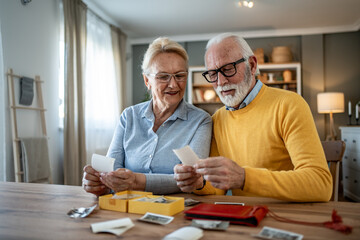 Happy senior couple viewing old photos at home