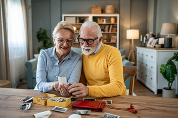 Senior couple watching old photos at home, remembering past times