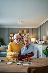 Happy senior couple enjoying photo album at home