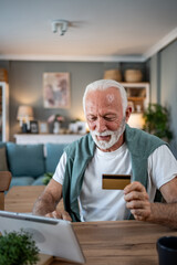 Senior man using tablet and credit card for online shopping at home
