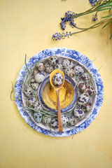 Easter table decor quail eggs on a blue plate on a yellow background, closeup