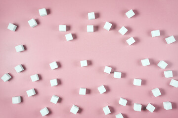 White sugar cubes scattered on pink background in random pattern.