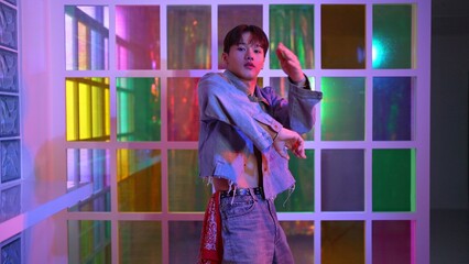 Close up of asian performer with sun glasses moving freestyle dance while looking at camera at nightclub. Happy street dancer dancing and show footstep with colorful bright neon light. Regalement.