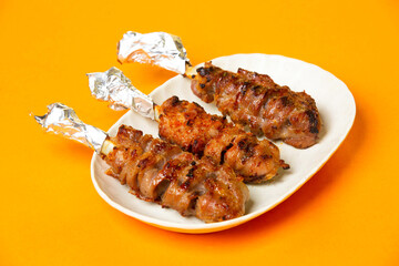 Grilled Piglet spleen skewers or Foil Handles served in basket isolated on orange background side view of hong kong food