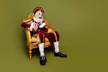 Elderly Gentleman in Renaissance Costume Sitting in Throne Chair on a Modern Khaki Background