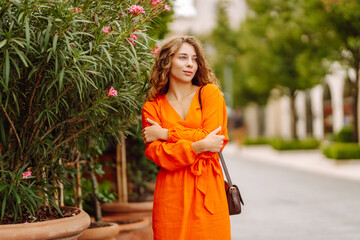 Cheerful tourist in a bright dress walks along a beautiful street. A young woman enjoys the weather...