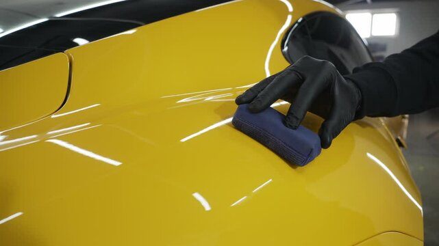 Process of applying a ceramic coating to the sports car surface for protection during detailing session at the service. Detailing ceramic polishing at the car service 4k video.