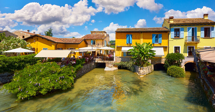 Old village Borghetto Valeggio sul Mincio, Veneto region, Italy. Colorful houses. Panoramic view at the town house on river. Sunny day with blue sky and clouds.