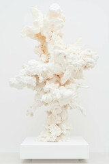 Abstract cloud-like white sculpture on display pedestal in art gallery