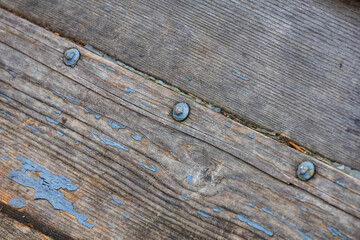 Abstract shot of old wood planks with peeling blue paint, held together by rusted iron nuts, from...