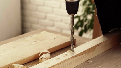 Discovering woodworking techniques while drilling into softwood at a workshop in a bright indoor space