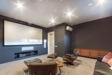 Private home cinema with a wide screen and modern equipment. Comfortable leather armchairs and a...