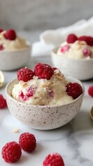 Creamy raspberry coconut ice cream in speckled bowls on marble surface