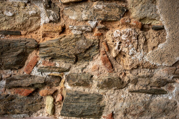 Close-up of an old stone wall showing various stones, bricks, and mortar with visible textures and colors