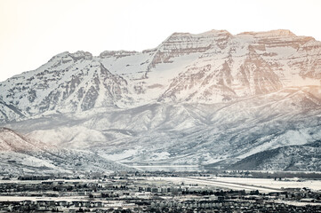 Snow covered mountain range towering over a suburban city in winter