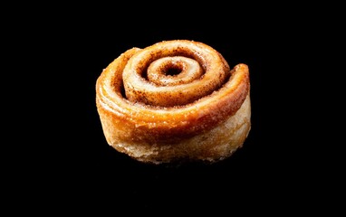 Fototapeta premium Golden Brown Glazed Cinnamon Roll on Black Background