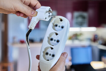 An electrical extension cord with tee became charred and caused short circuit due to overload.