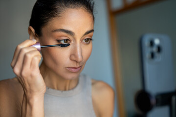 Woman Applying Mascara While Filming Makeup Tutorial