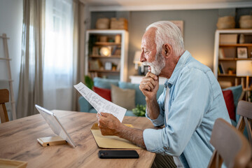 Senior man reading documents and thinking at home