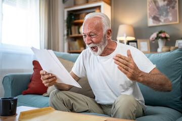 Shocked senior man reading bad news in a letter at home