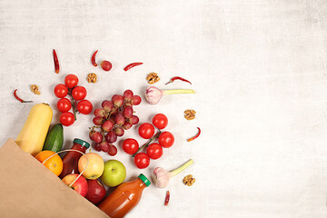 Paper eco bag with healthy vegan products for weight loss. Grapes, oranges, tomatoes, apples, bananas and natural juice in a craft bag on a concrete background, food delivery concept,