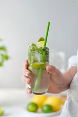 Hand holding glass with mojito cocktail drink, summer refreshing beverage, lifestyle