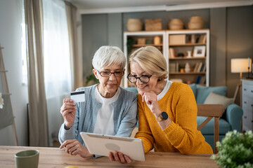 Senior women making online purchase using digital tablet and credit card at home