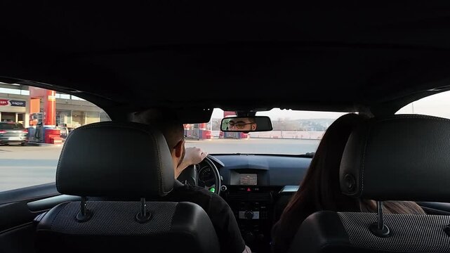 Couple riding in the car pulling from a main road to a gas station