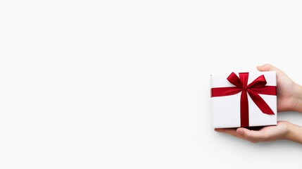 A person holding a white gift box with a red ribbon