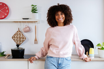Happy young adult Latin American woman smiling at camera standing at modern kitchen at home