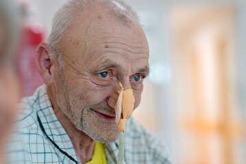 Patient with nasogastric tube on hospital bed waiting for treatment. Positive close up of an elder man waiting for an operation. Enthusiastic approach to hospital treatment..
